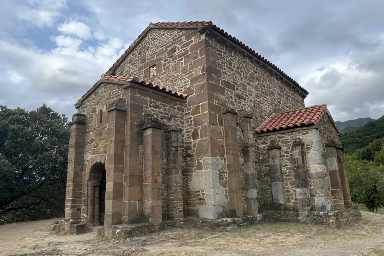 Santa Cristina de Lena, iglesia prerrománica de piedra sobre una colina, con montes verdes al fondo