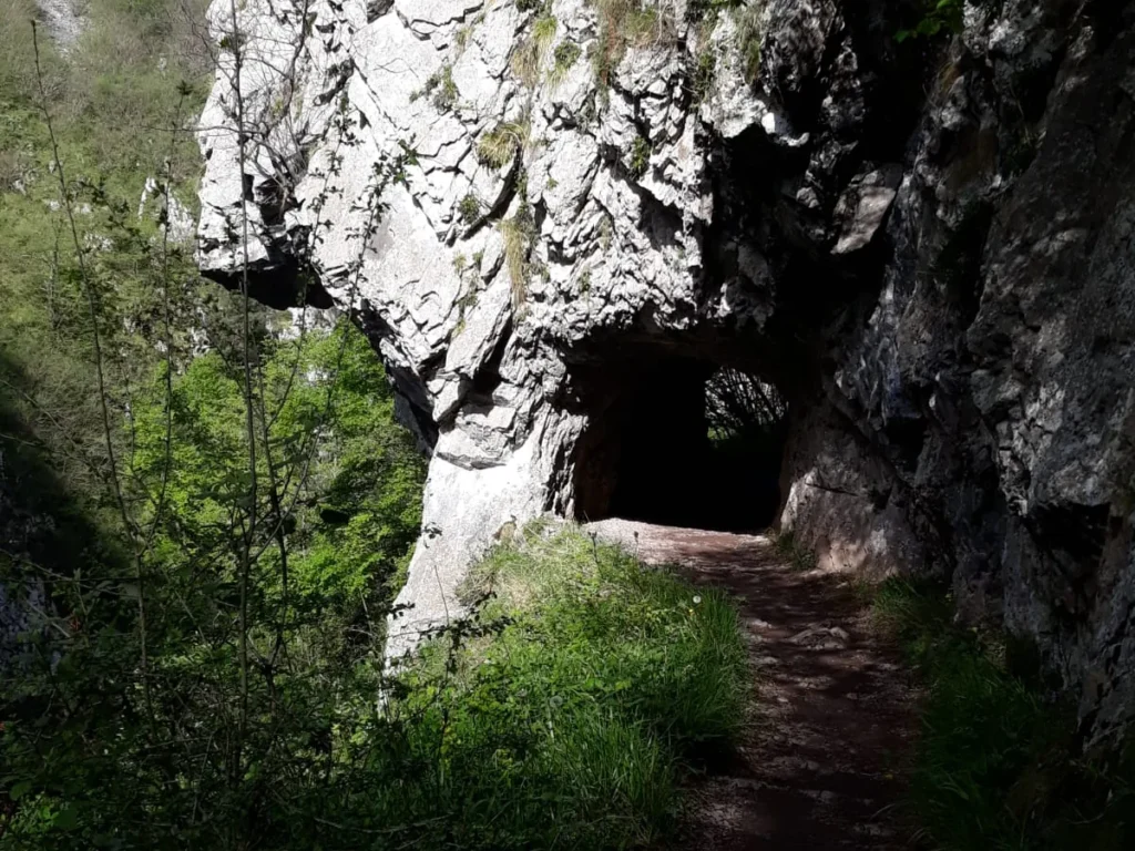La senda del desfiladero de las Xanas, tallada en la roca, con la boca de un túnel