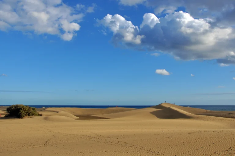 Dunas de Maspalomas con el mar al fondo y nubes sobre un cielo azul