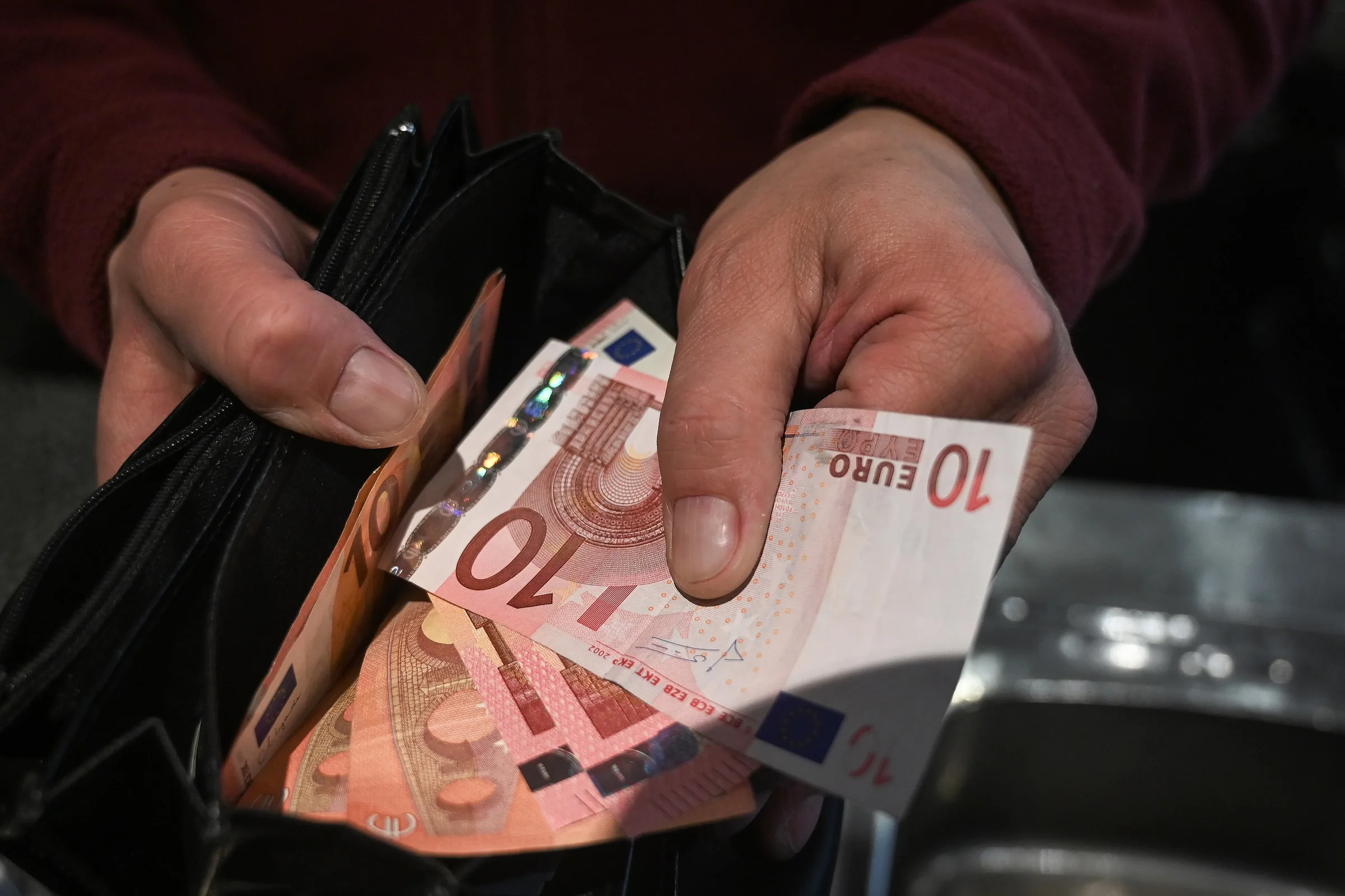Manos que sacan billetes de 10 euros de una cartera