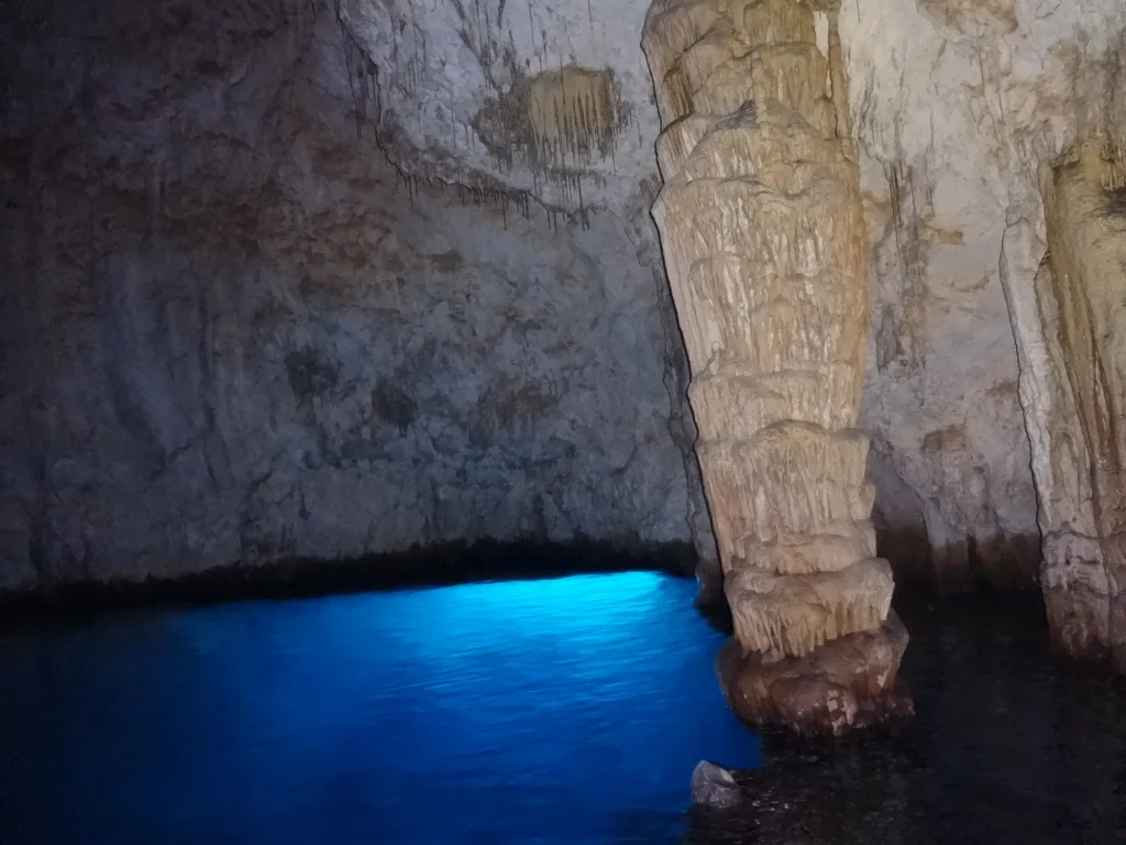 Interior de la Grotta dello Smeraldo, con el agua iluminada y columnas de roca
