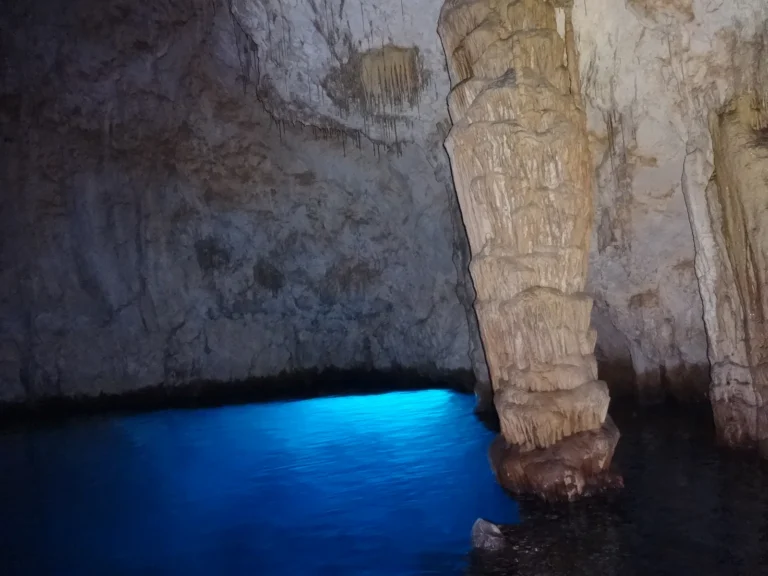 Interior de la Grotta dello Smeraldo, con el agua iluminada y columnas de roca