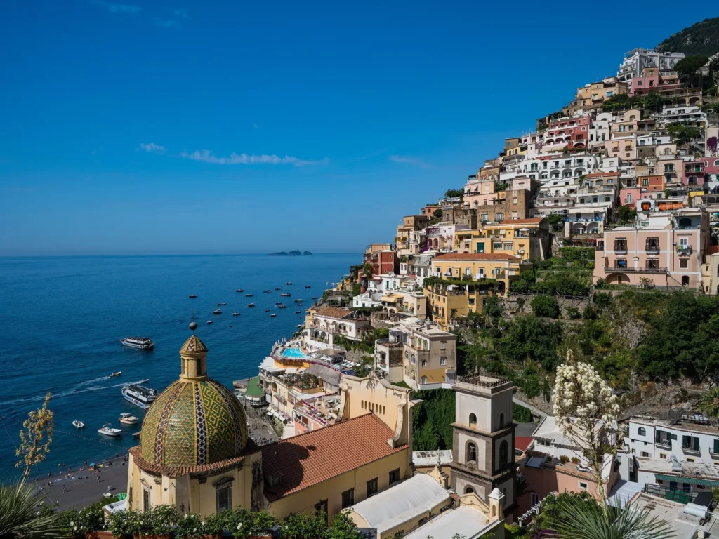 Cúpula de mayólica de la iglesia de Santa Maria Assunta y las casas de Positano sobre el mar