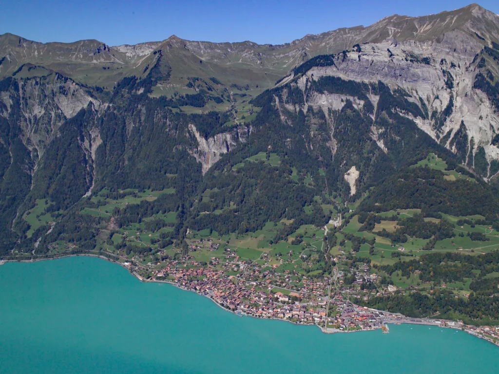 El lago de Brienz, de color turquesa, con el pueblo en la orilla y las montañas detrás