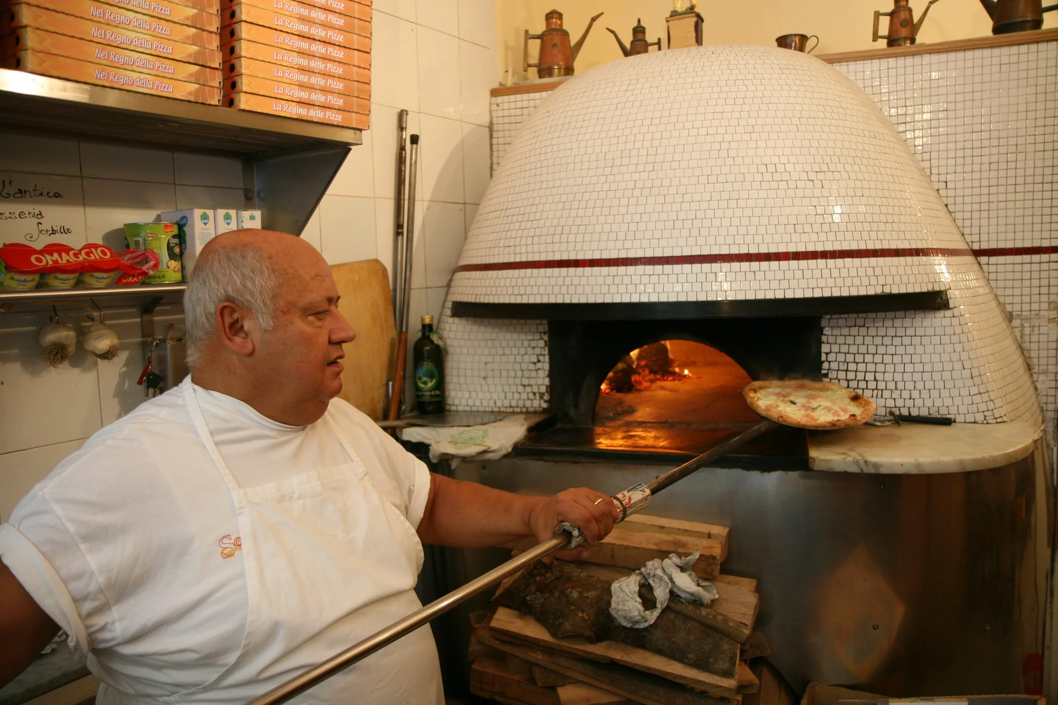 Un pizzero mete una pizza en el horno de leña de la pizzería Sorbillo, en Nápoles