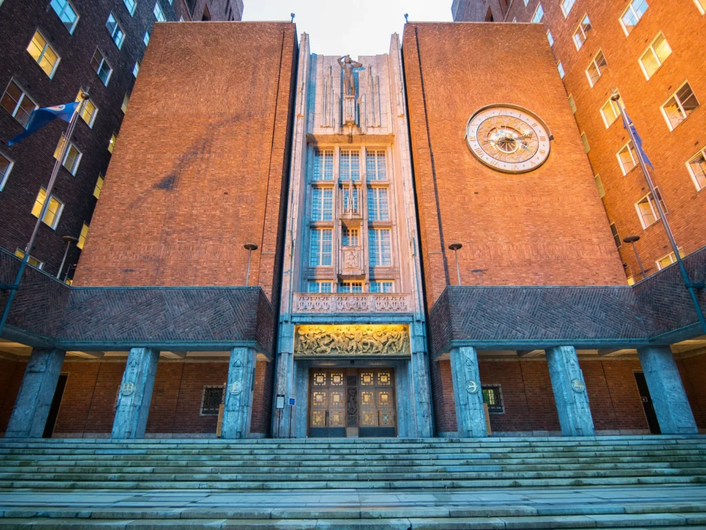 Fachada de ladrillo del Ayuntamiento de Oslo, con su reloj y la escalinata de entrada