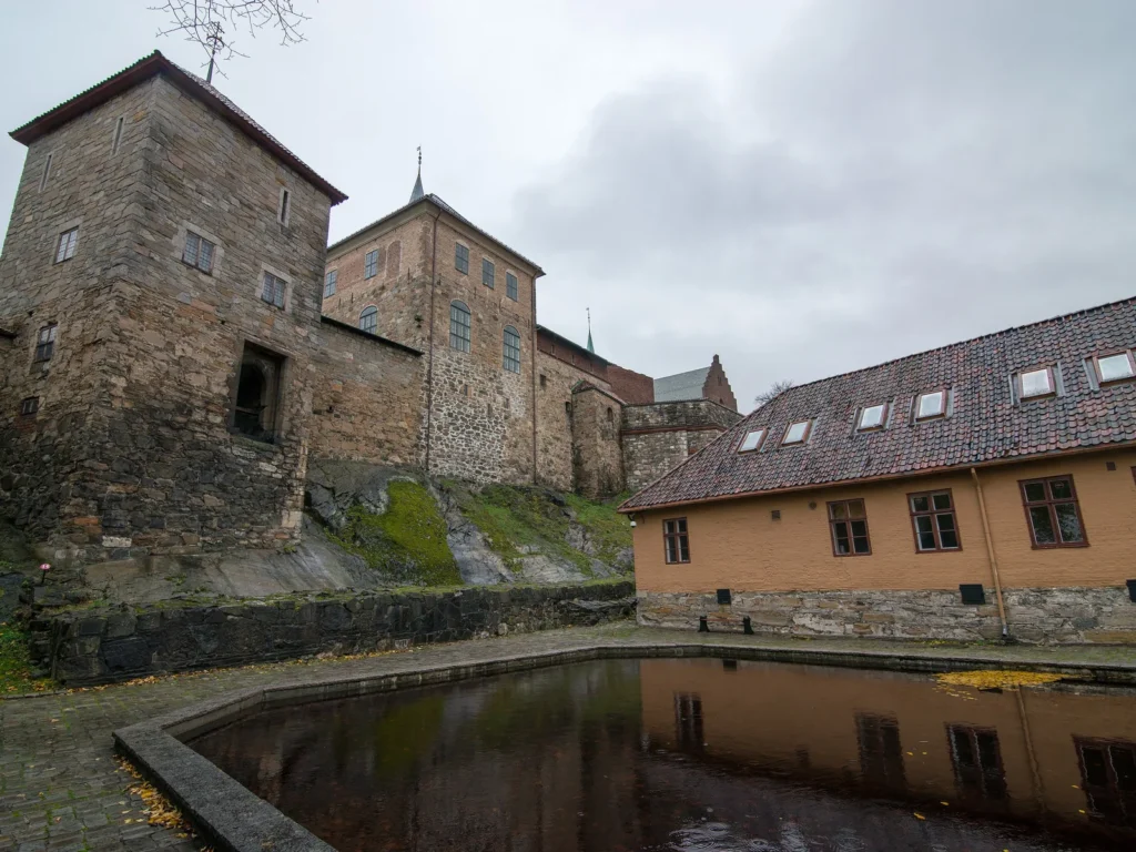 Torres de piedra del castillo de Akershus reflejadas en un estanque del recinto