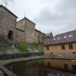 Torres de piedra del castillo de Akershus reflejadas en un estanque del recinto