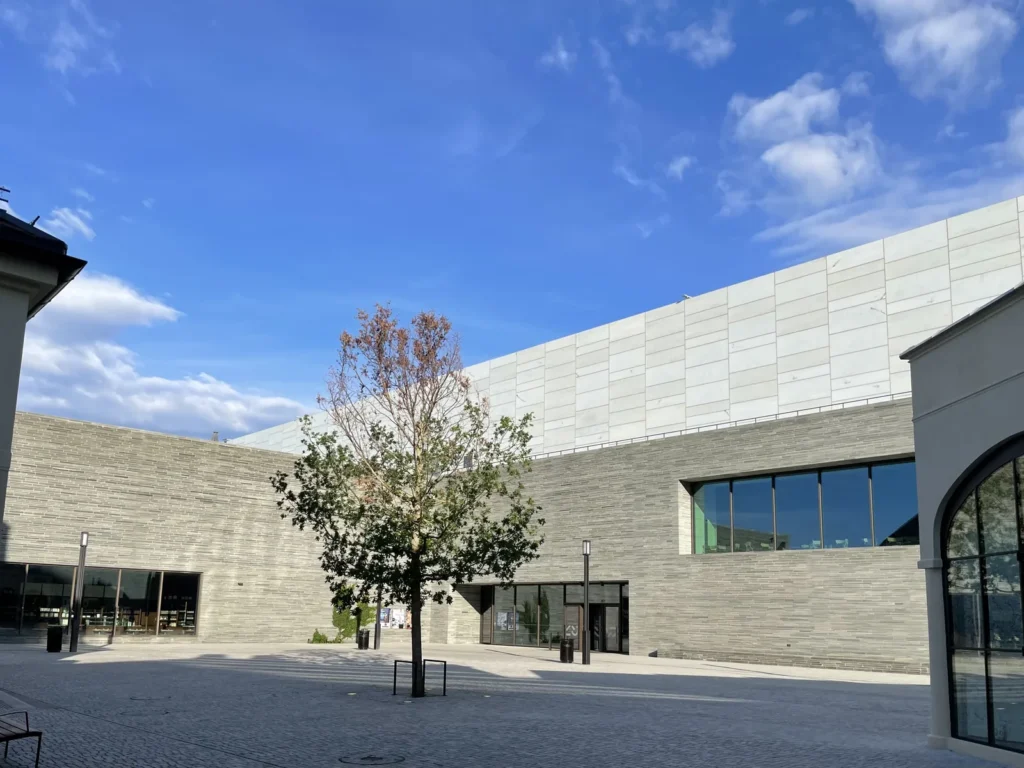 Fachada de piedra gris del Nasjonalmuseet, con un árbol en flor delante