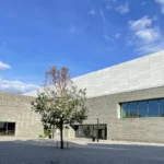 Fachada de piedra gris del Nasjonalmuseet, con un árbol en flor delante