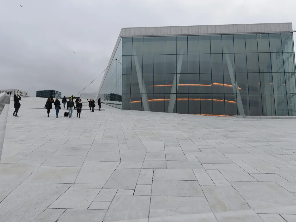 Gente caminando por el tejado de mármol blanco de la Ópera de Oslo