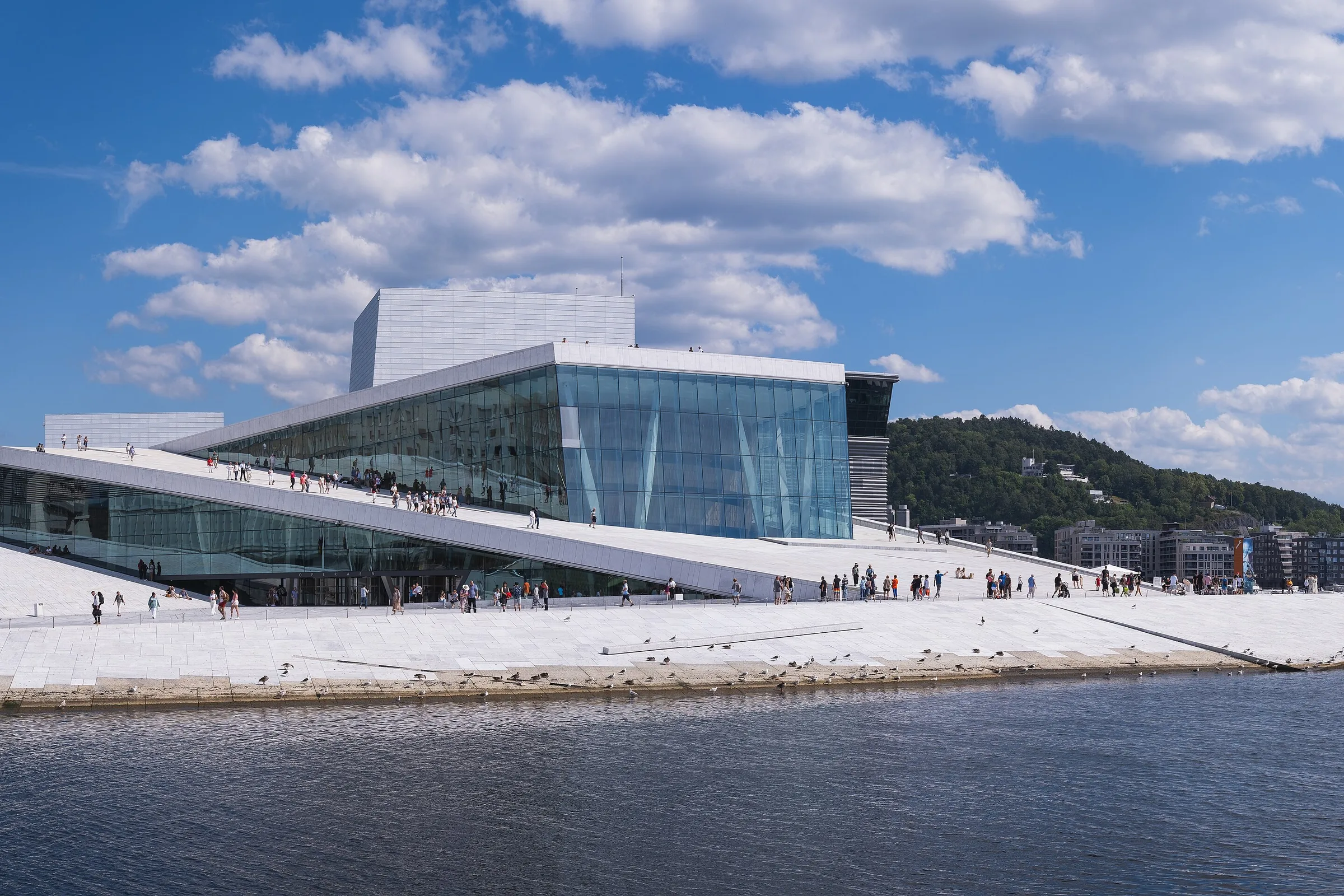 La Ópera de Oslo, blanca, junto al agua del fiordo en un día de cielo azul